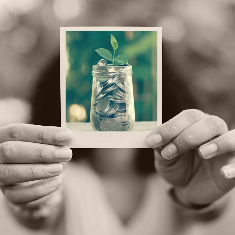 Woman holding a polaroid photo of a jar of quarters