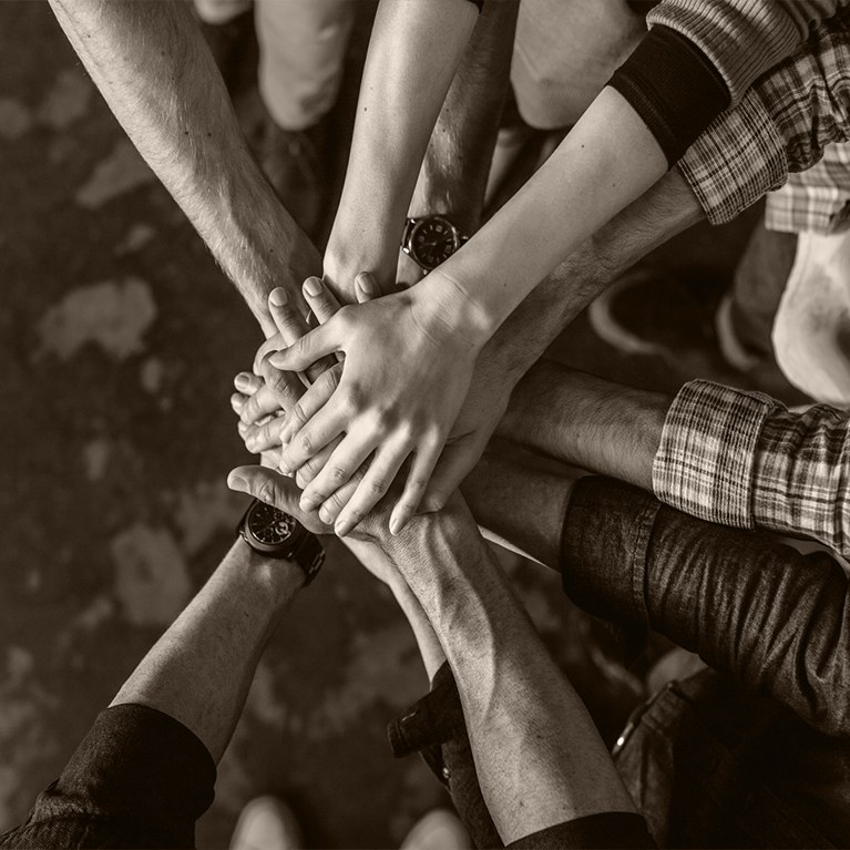 Group of people in a circle with hands stacked on top of each other