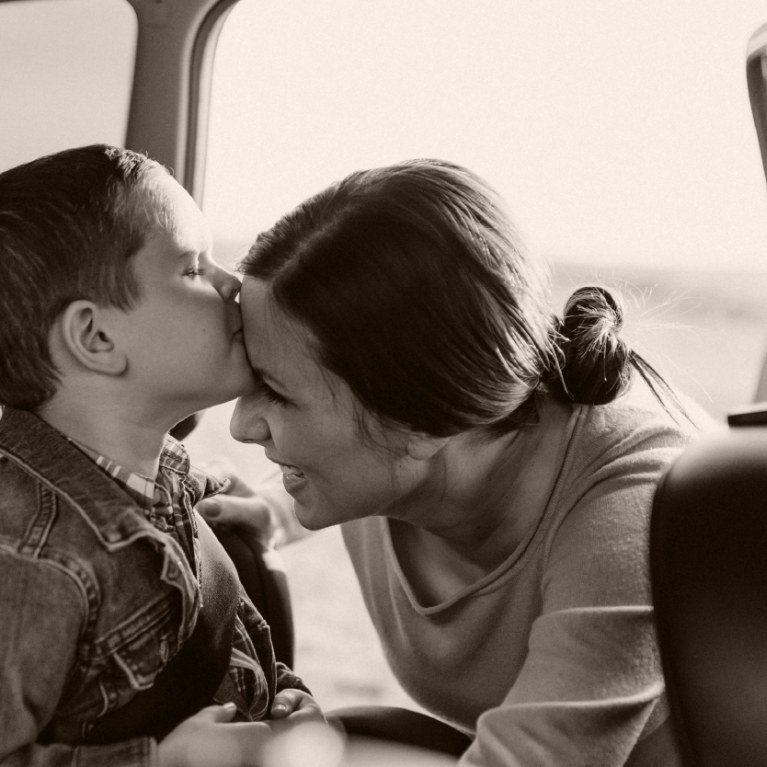 child in backseat kissing mom on cheek after being buckled in