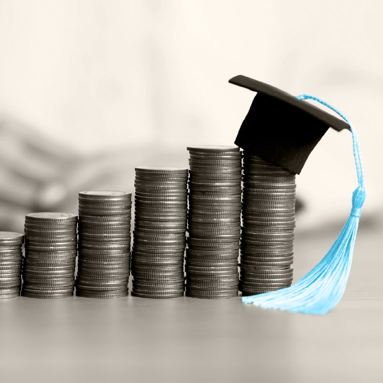 blue graduation cap tassel on stacks of coins