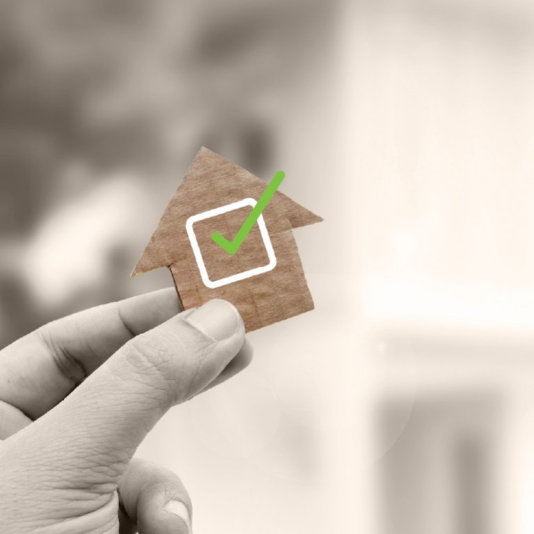hand holding a house with a green checkmark