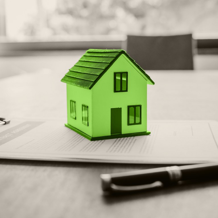 green house on top of a home loan application  on a desk with a pen