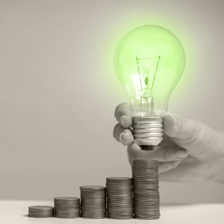 a green lightbulb over money