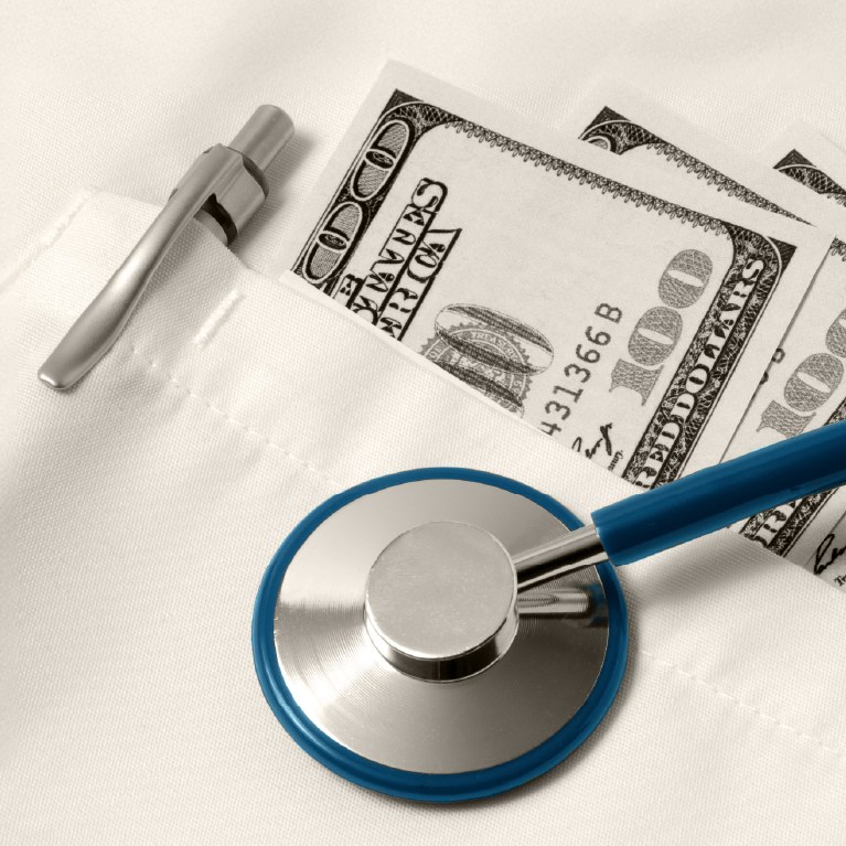 medical coat pocket with cash under a stethoscope