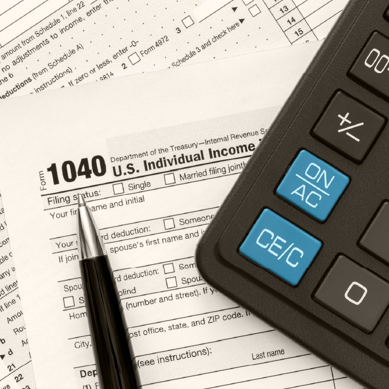 tax form with calculator next to it and a pen and paper