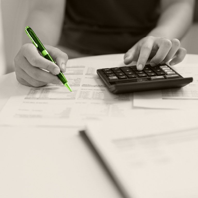 hand writing and checking budget with a calculator