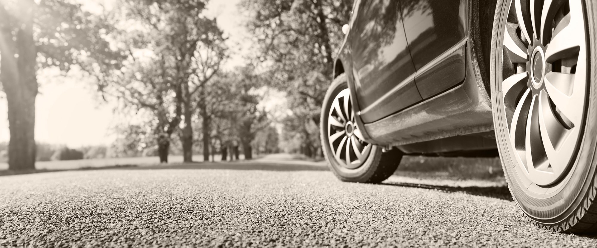 an angled  view of sedan tires on asphalt