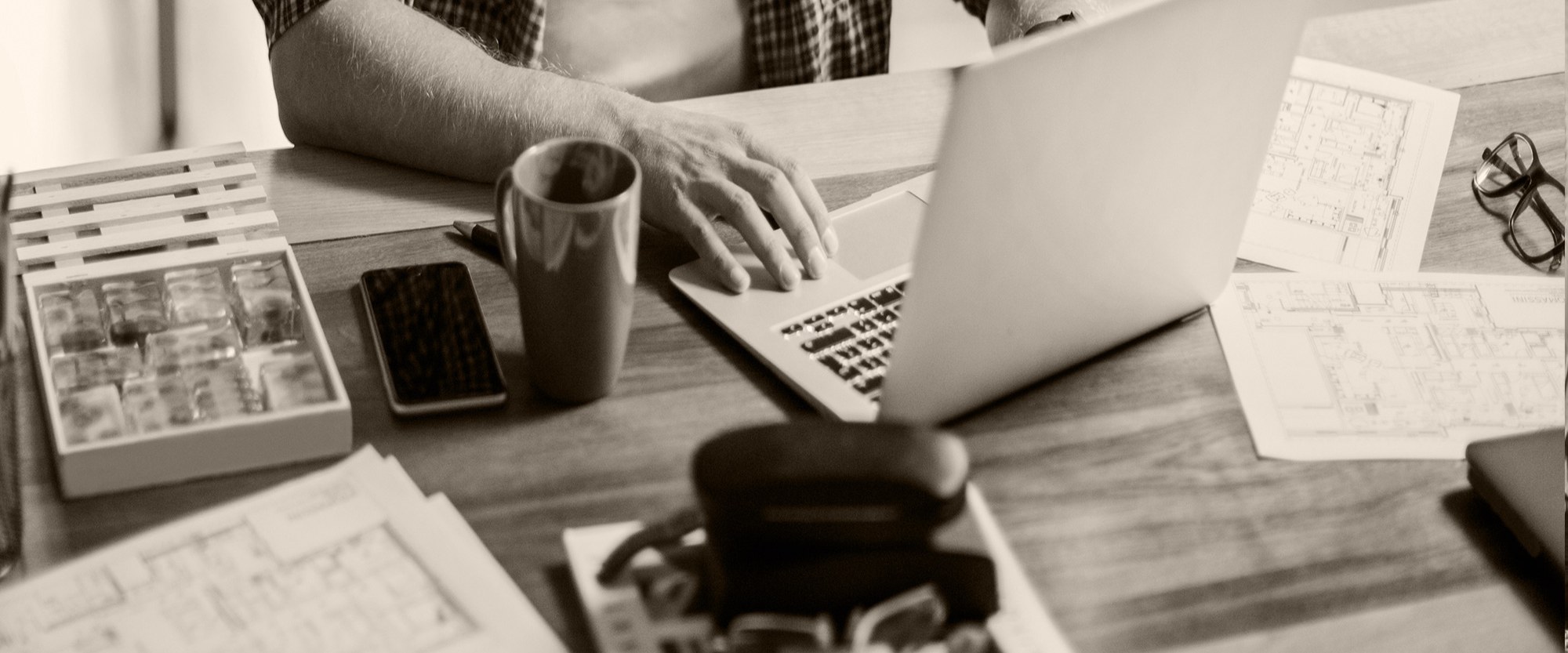 man at laptop with cup of coffee and calculator on table