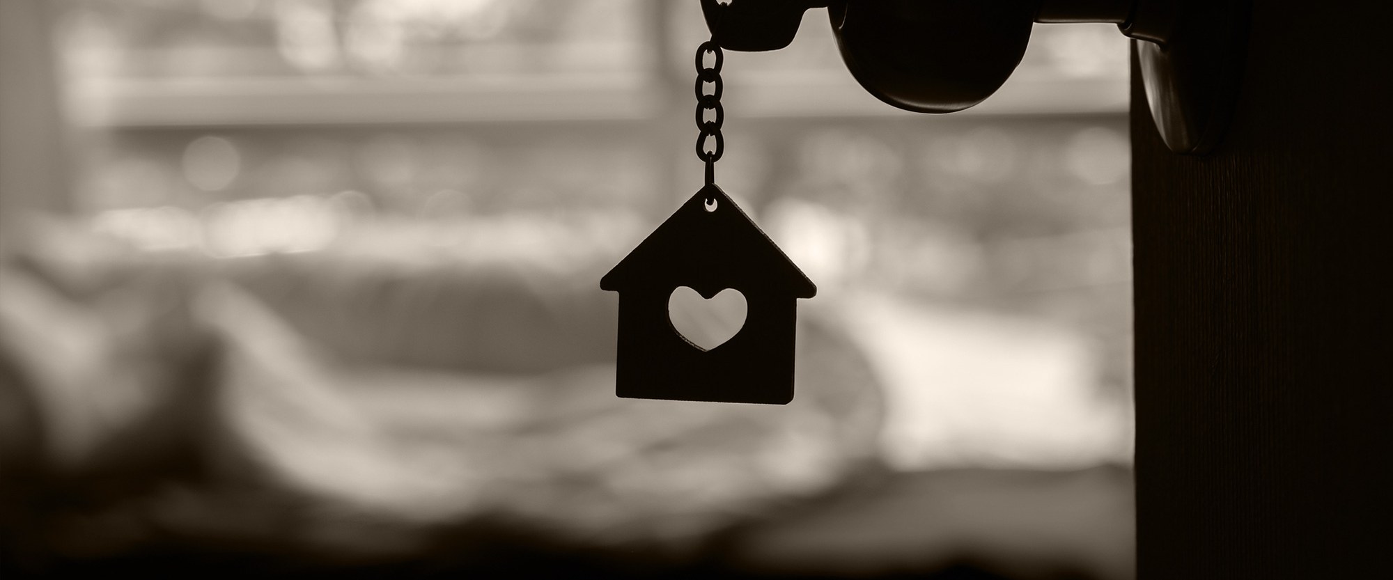 Key in door with a house with a heart keychain dangling
