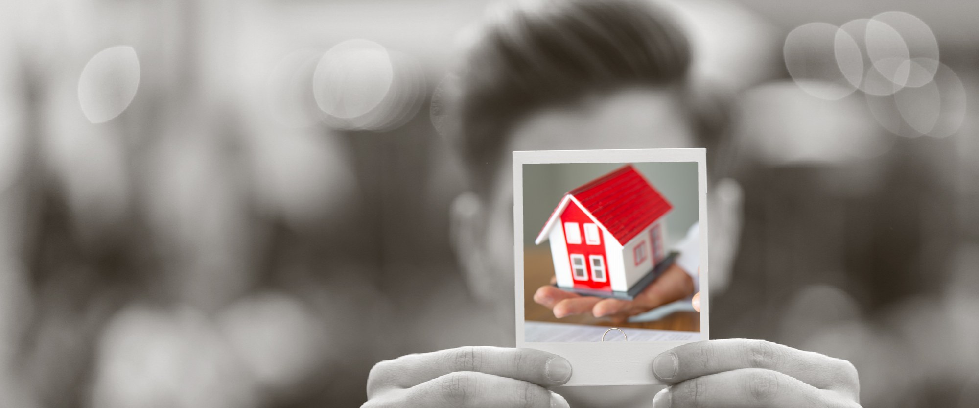 person holding a polaroid of a house