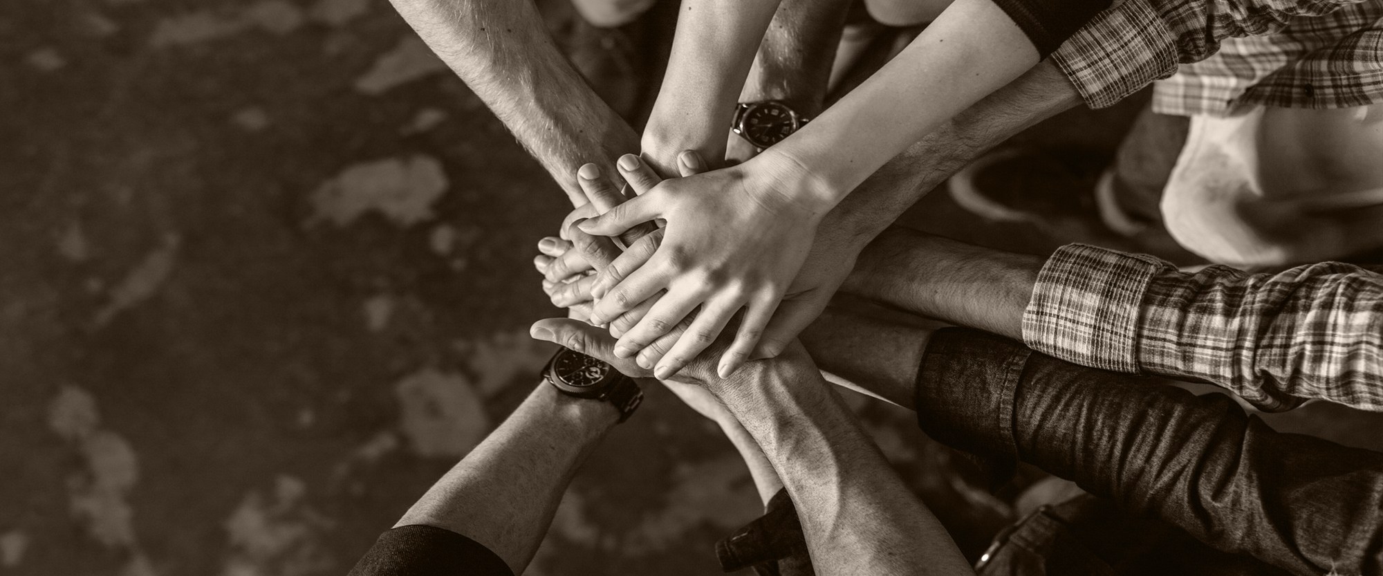 Group of people in circle with hands stacked together.