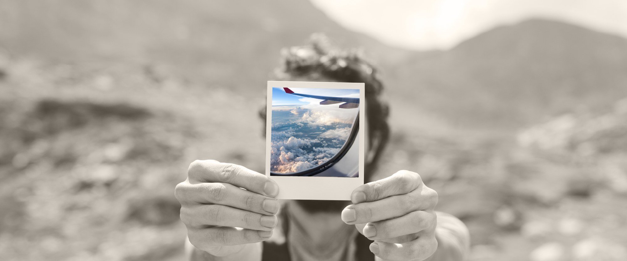 Person holding polaroid picture of airline flight