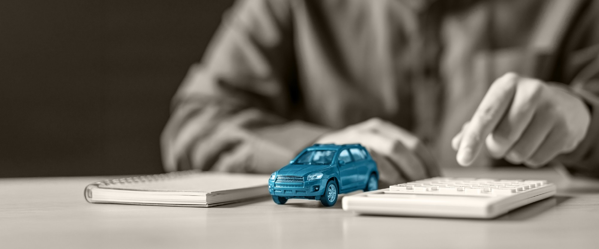 teal wooden auto on desk next to calculator