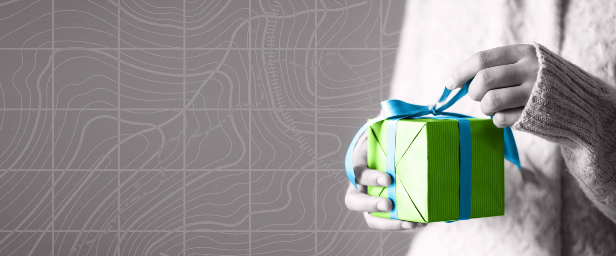 person holding a green wrapped box with a blue ribbon