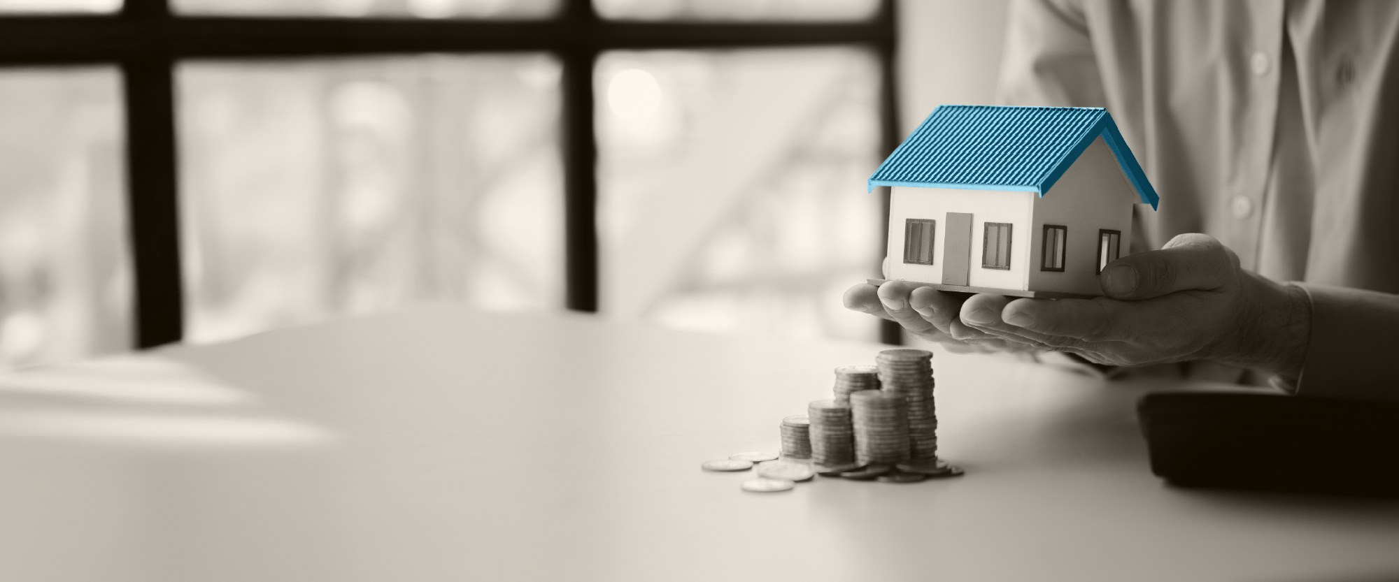 hand holding house with teal roof