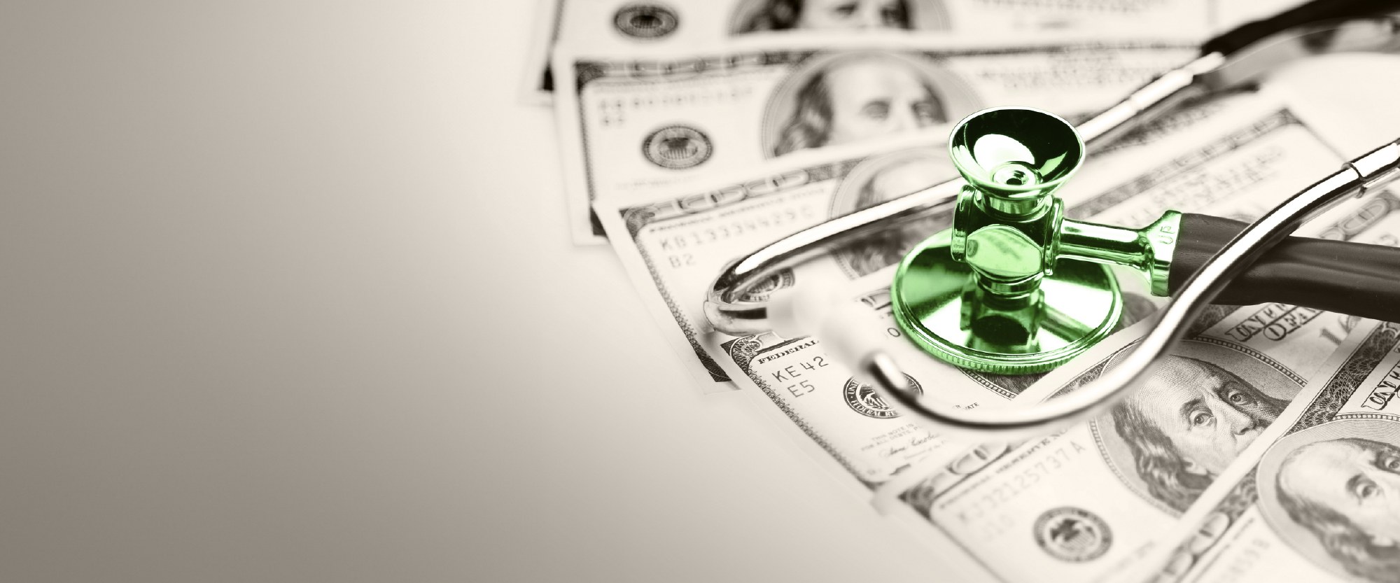 green stethoscope over hundred dollar bills