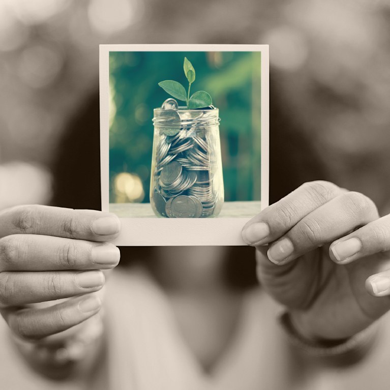 Woman holding a polaroid photo of a jar of quarters