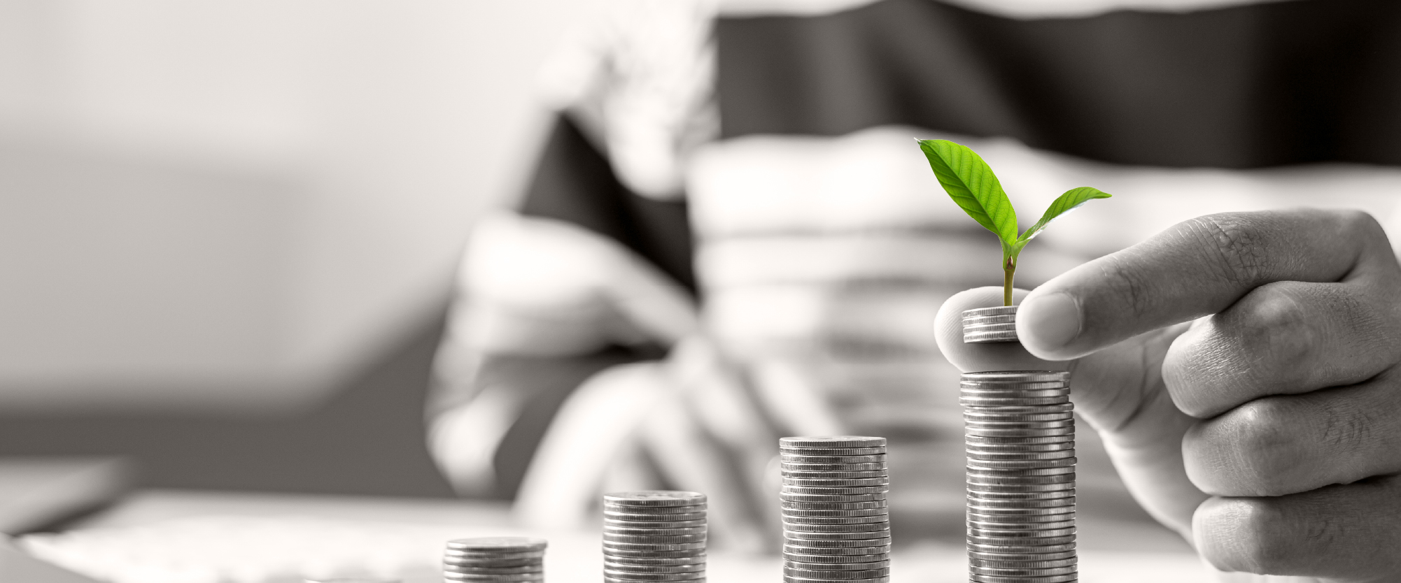 hand stacking increasing row of coins with a plant growing the top