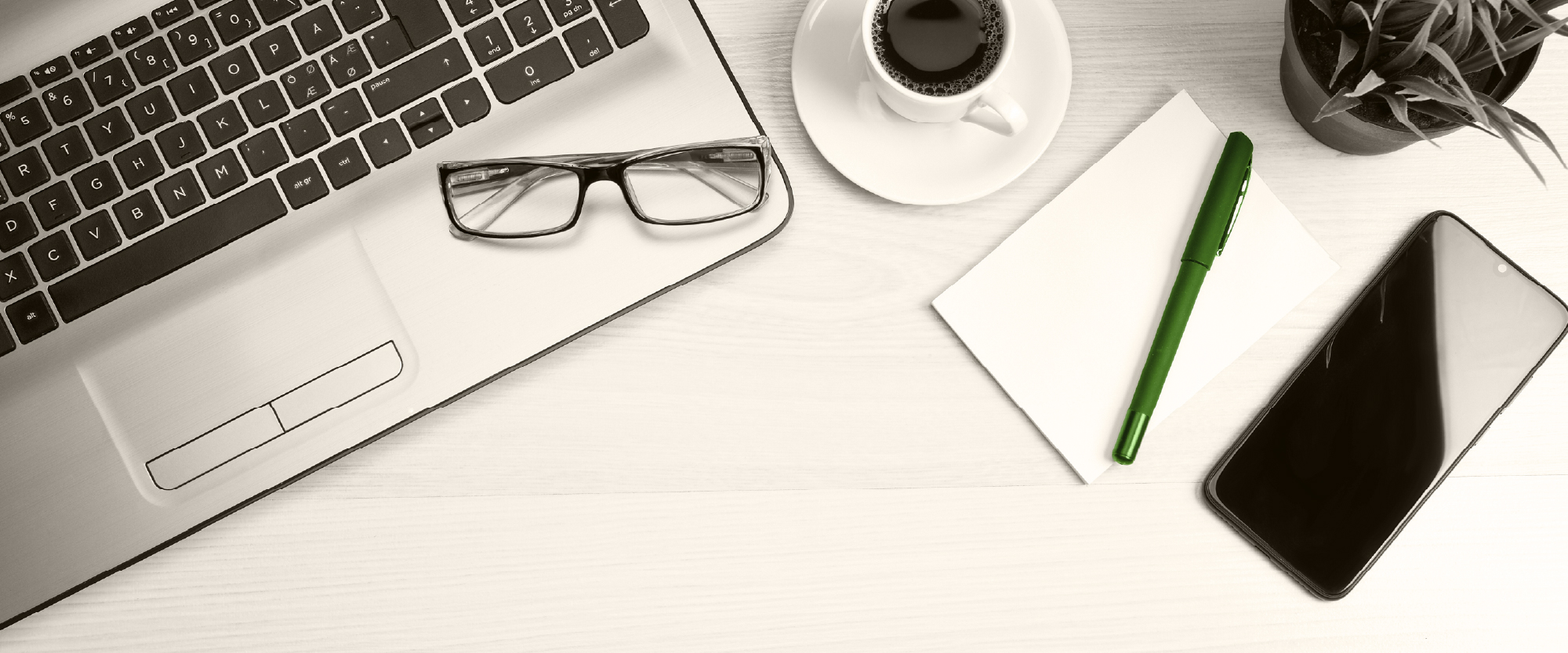 desk with laptop and phone with a cup of coffee next to them