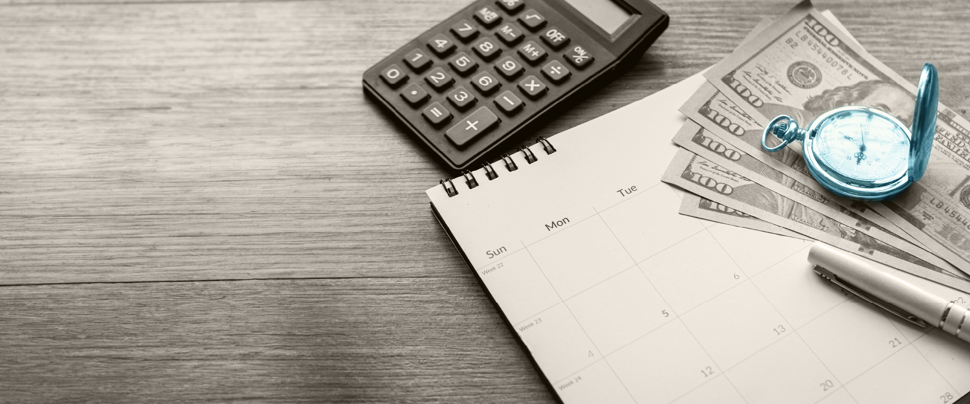 blue watch over some money and a calendar on a desk with a calculator