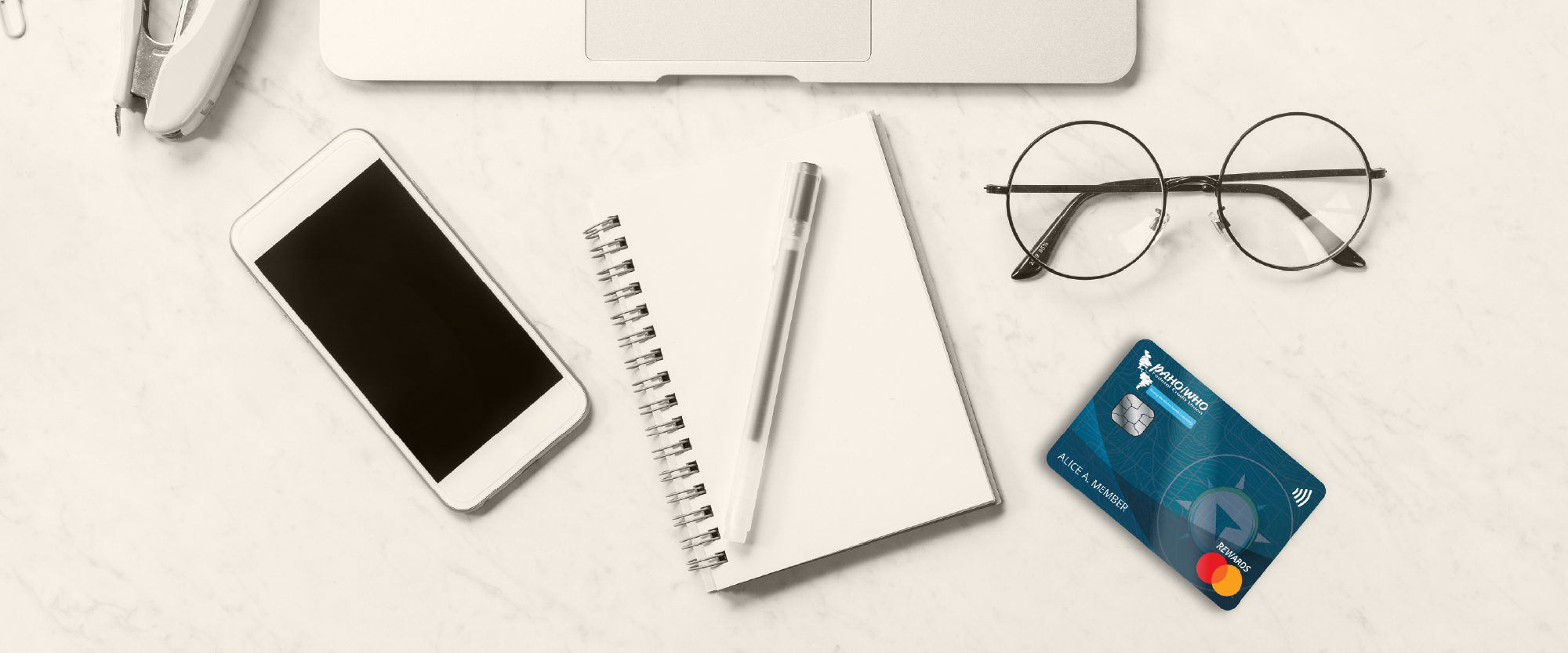 credit card on a desk next to glasses and laptop