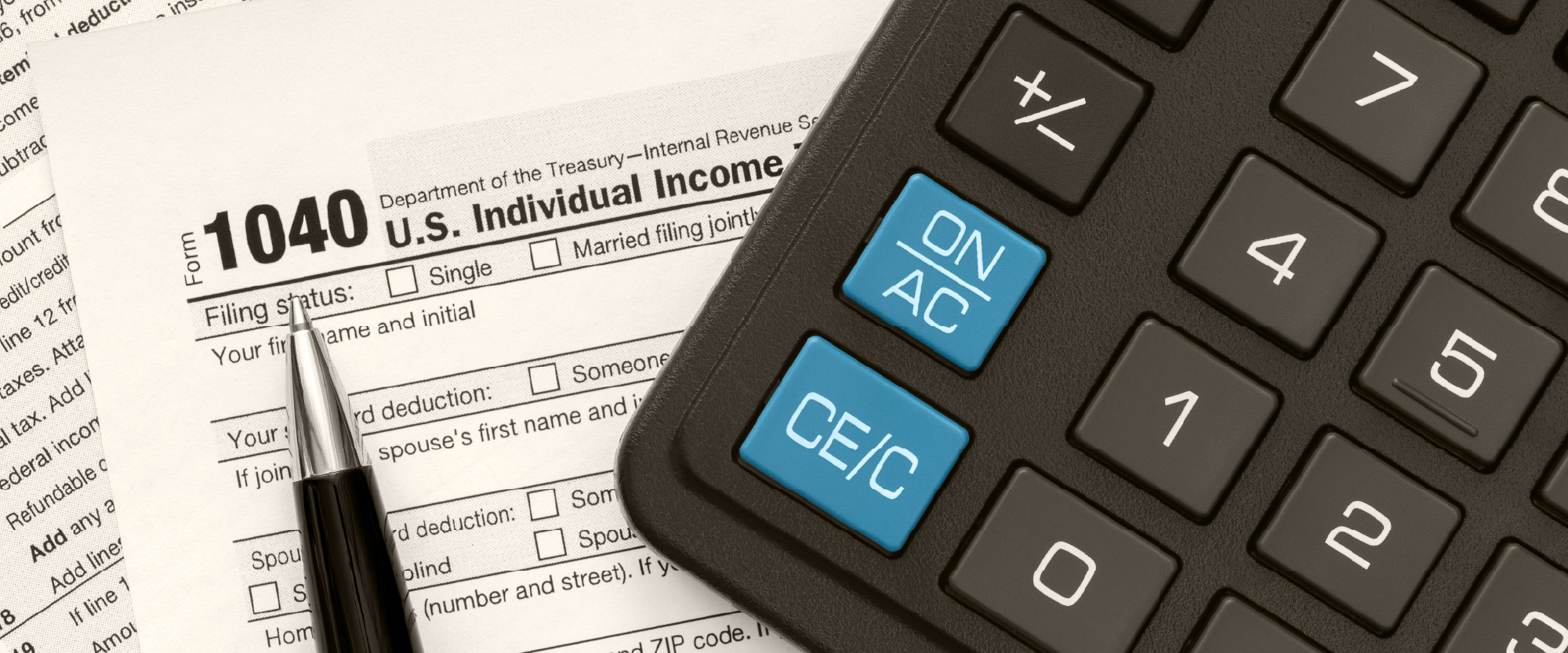 tax form with calculator next to it and a pen and paper