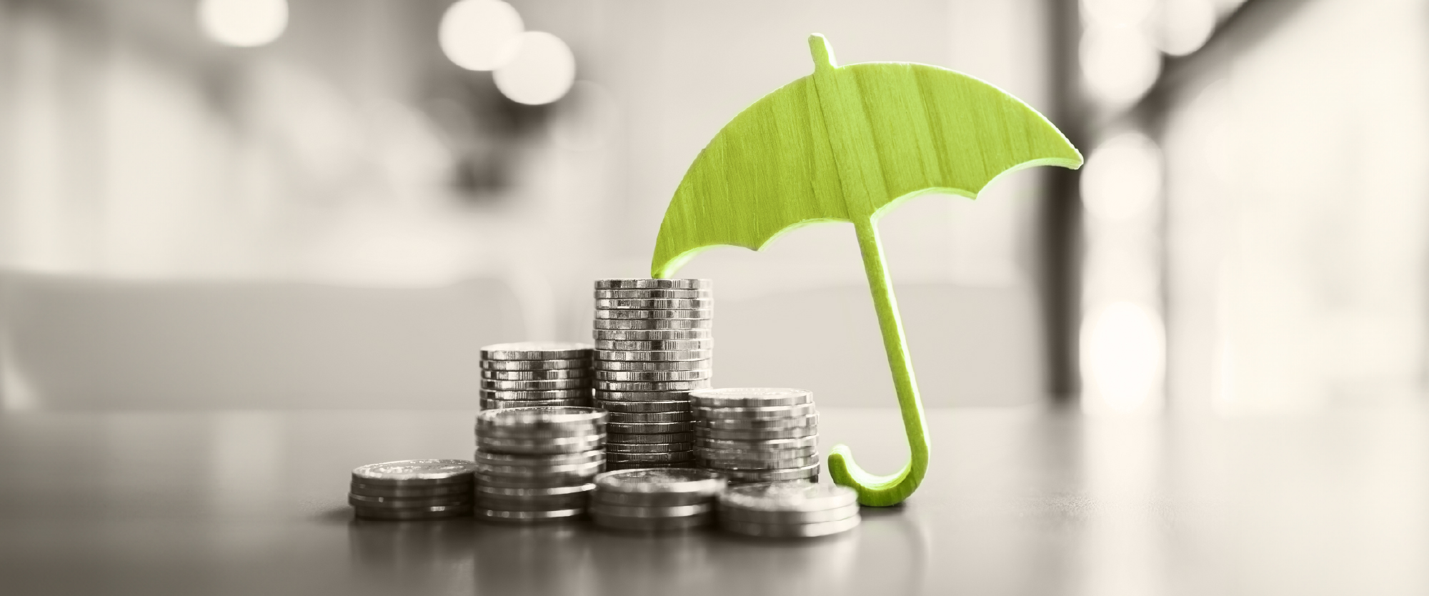 green umbrella with coins on a desk
